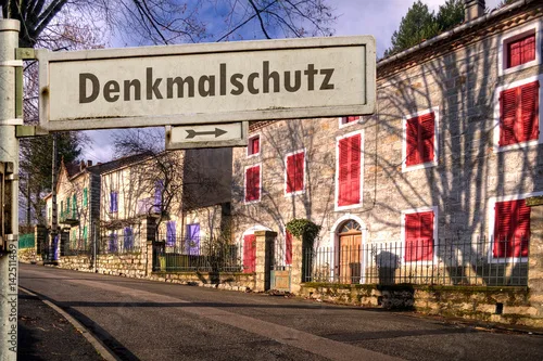 Straßenschild mit der Aufschrift „Denkmalschutz“ vor einer unsanierten Altbauzeile